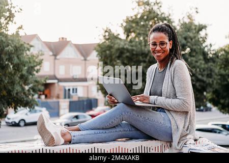 Felice donna matura seduta sul muro in terrazza Foto Stock