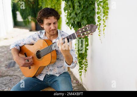 Chitarrista di flamenco eseguito da pareti bianche con piante di edera Foto Stock