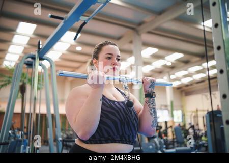 Donna in sovrappeso che fa esercizio di peso in palestra Foto Stock