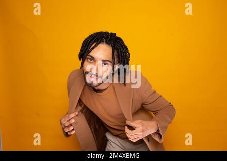 Uomo sorridente con dreads che si posano su sfondo giallo Foto Stock
