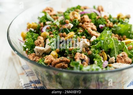 Insalata fatta in casa con kale, lenticchie, olive, noci e feta vegana. Foto Stock