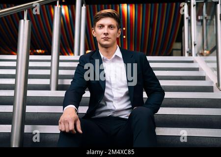 Giovane uomo d'affari seduto sulla scala Foto Stock