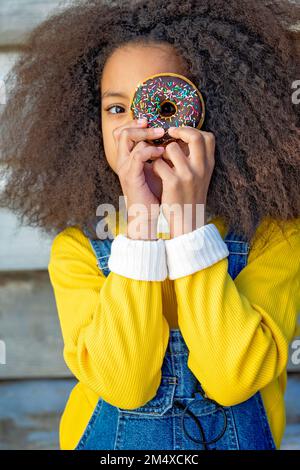 Ragazza che guarda attraverso il foro di ciambella Foto Stock