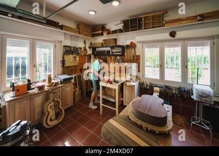 Luthier che lavora alla chitarra in officina Foto Stock