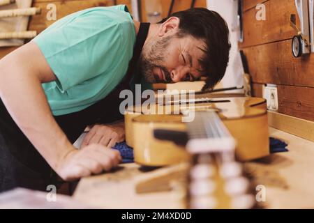 Luthier esaminano la chitarra in officina Foto Stock