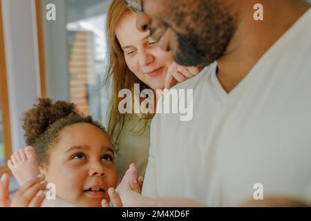 Felice padre e madre con la figlia che tiene le gambe della bambina Foto Stock