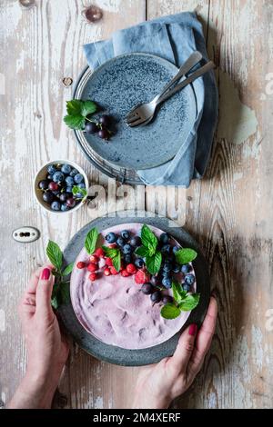 Mani di donna che raccolgono il piatto con la torta di acacero vegano Foto Stock