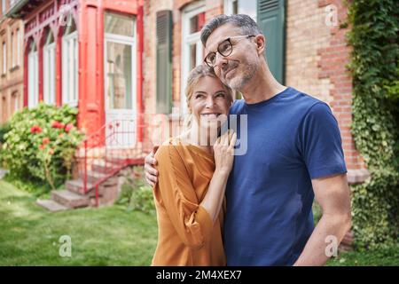 Coppia sorridente che si abbraccia nel cortile posteriore Foto Stock