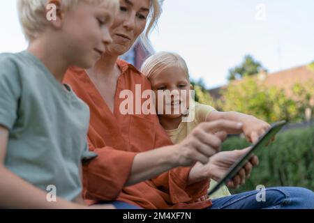 Donna che usa un tablet PC seduto con bambini Foto Stock