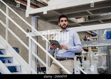 Uomo d'affari premuroso in piedi con PC tablet sulla scala Foto Stock