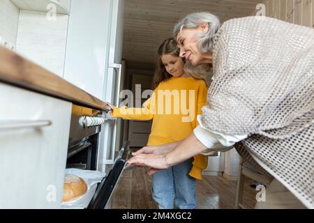 Nonna e nipote che prendono pane fatto in casa appena sfornato dal forno Foto Stock