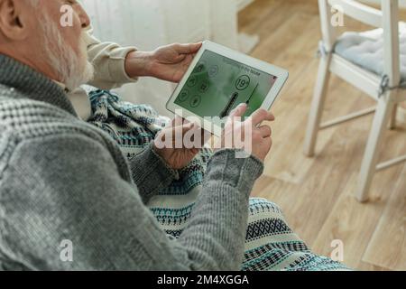 Uomo che regola la temperatura su un dispositivo smart home Foto Stock