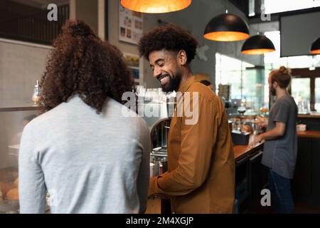 Barista sorridente che parla con un collega nel bar Foto Stock