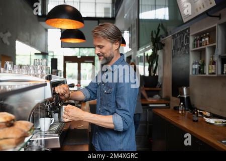 Barista sorridente che prepara il latte nel bar Foto Stock