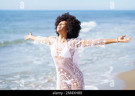 Donna spensierata in piedi con le braccia distese in spiaggia Foto Stock