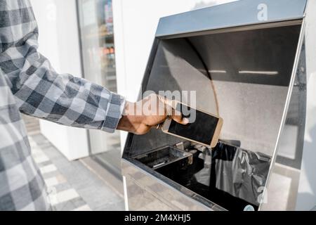 Uomo che trasla uno smartphone nel cestino Foto Stock