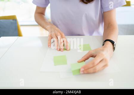 Mani di freelance che attaccano le note adesive sulla carta a casa Foto Stock