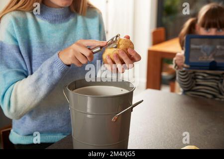 Ragazza che sbuccia patate in cucina a casa Foto Stock