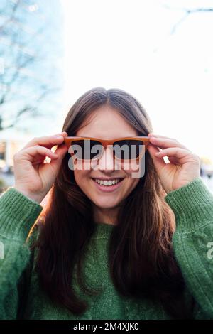 Felice giovane donna che indossa gli occhiali da sole Foto Stock