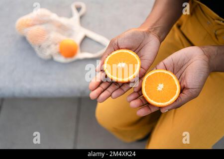 Donna che tiene in mano fette di arance Foto Stock