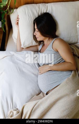 Donna matura incinta che dorme a letto a casa Foto Stock
