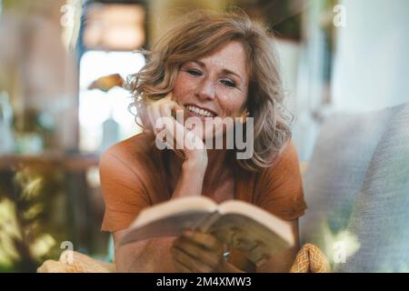 Sorridente donna matura libro di lettura Foto Stock