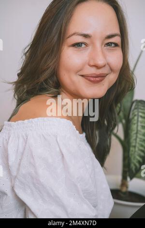 Donna bella sorridente in bianco fuori dalla spalla Foto Stock