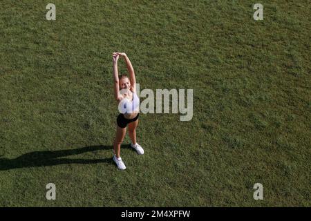 Felice giovane donna che si allunga nel parco Foto Stock