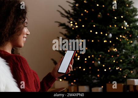 Donna sorridente con il telefono cellulare a casa Foto Stock