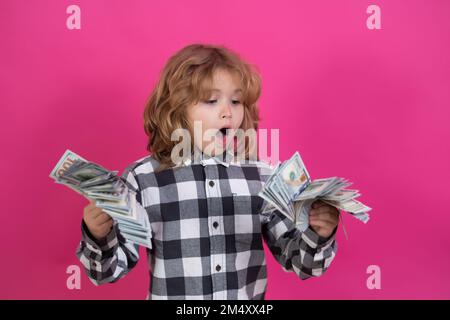 Capretto che mostra le fatture del dollaro dei soldi, sognando levante in piedi dei ricchi contro lo sfondo rosso isolato dello studio rosa. Foto Stock