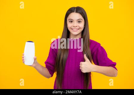 Ragazza adolescente con balsamo shampoo o gel doccia. Prodotti cosmetici per la cura dei capelli per bambini, bottiglia di shampoo. Foto Stock