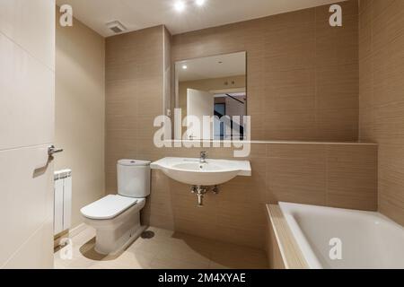 Bagno con lavello in porcellana bianca senza armadio, ripiano incorporato, specchio quadrato senza cornice e vasca in porcellana Foto Stock