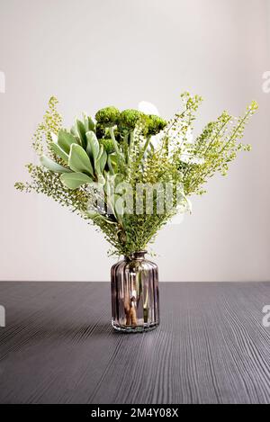 composizione floreale in vaso di vetro, un bouquet di fiori misti da crisantemi verdi nel soggiorno su un tavolo nero Foto Stock