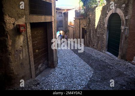 Stretta strada acciottolata che conduce ad un passaggio coperto in un vecchio villaggio Foto Stock