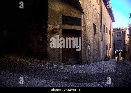 Stretta strada acciottolata che conduce ad un passaggio coperto in un vecchio villaggio Foto Stock