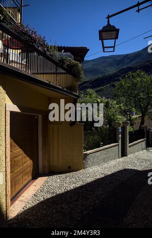 Stretta strada acciottolata che conduce ad un passaggio coperto in un vecchio villaggio Foto Stock