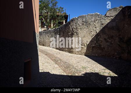 Stretta strada acciottolata che conduce ad un passaggio coperto in un vecchio villaggio Foto Stock