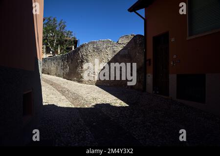 Stretta strada acciottolata che conduce ad un passaggio coperto in un vecchio villaggio Foto Stock