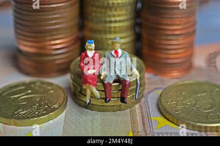 Abstract figure isolate di una coppia anziana in pensione seduta su una pila di monete in euro - concetto di pensione e risparmio pensionistico Foto Stock