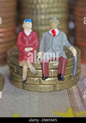 Abstract figure isolate di una coppia anziana in pensione seduta su una pila di monete in euro - concetto di pensione e risparmio pensionistico Foto Stock