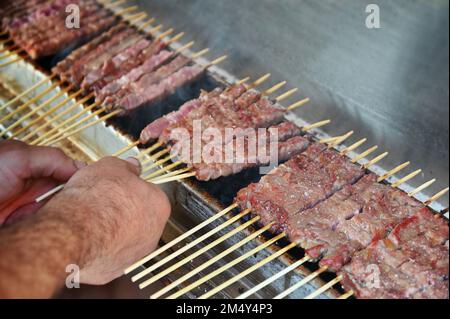 Arrostire i tradizionali arrosticini italiani su una griglia Foto Stock