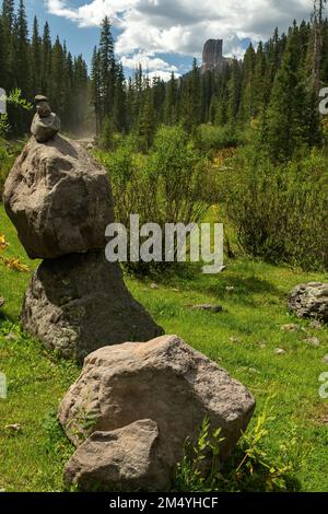 Chimney Rock lungo Owl Creek Pass, visto dietro rocce impilate vicino alla strada. Vicino al lago artificiale Silver Jack, Colorado Foto Stock