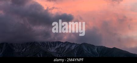 Panorama di nuvole temporesche che si snodano sulle montagne innevate al tramonto vicino a Bishop in California, USA Foto Stock