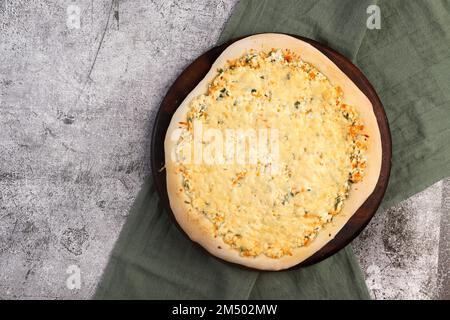 Pizza casereccia con formaggio su un tagliere di legno rotondo su uno sfondo grigio scuro. Vista dall'alto, disposizione piatta Foto Stock