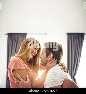 Il tuo sorriso fa saltare il mio cuore un battito. una giovane coppia felice che condivide un momento affettuoso a letto. Foto Stock