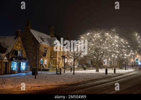 Luci di Natale lungo la strada alta di notte nella neve. Broadway, Cotswolds, Worcestershire, Inghilterra Foto Stock