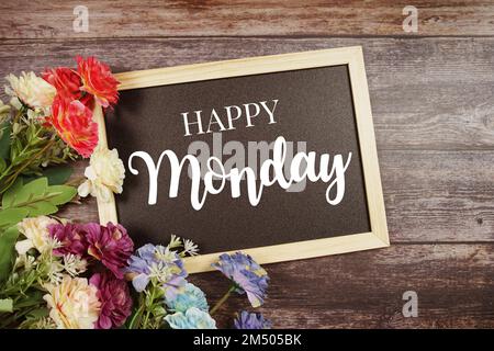 Buon lunedì testo tipografico e decorazione floreale su sfondo lavagna Foto Stock