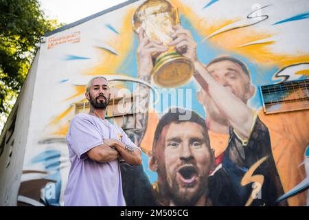 Buenos Aires, Argentina. 23rd Dec, 2022. L'artista, Maximiliano Bagnasco, si pone davanti al suo lavoro a Buenos Aires. L'artista argentino Maximiliano Bagnasco è il primo a catturare il trionfo dell'Argentina in Qatar 2022 in un murale in cui Lionel messi è visto sollevare la Coppa del mondo FIFA nel quartiere di Palermo, Buenos Aires. (Foto di Diego Radames/SOPA Images/Sipa USA) Credit: Sipa USA/Alamy Live News Foto Stock