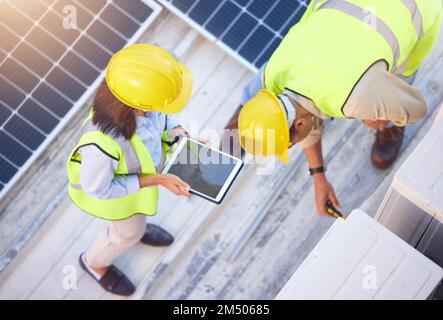 Vista dall'alto, lavoro di squadra e ingegneri con tablet sul tetto solare per manutenzione, ispezione o installazione. Energia solare, energia rinnovabile e uomo e. Foto Stock