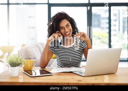Ascoltare attentamente. una giovane donna d'affari attraente seduta da sola nella sua casa e parlando sul suo cellulare. Foto Stock